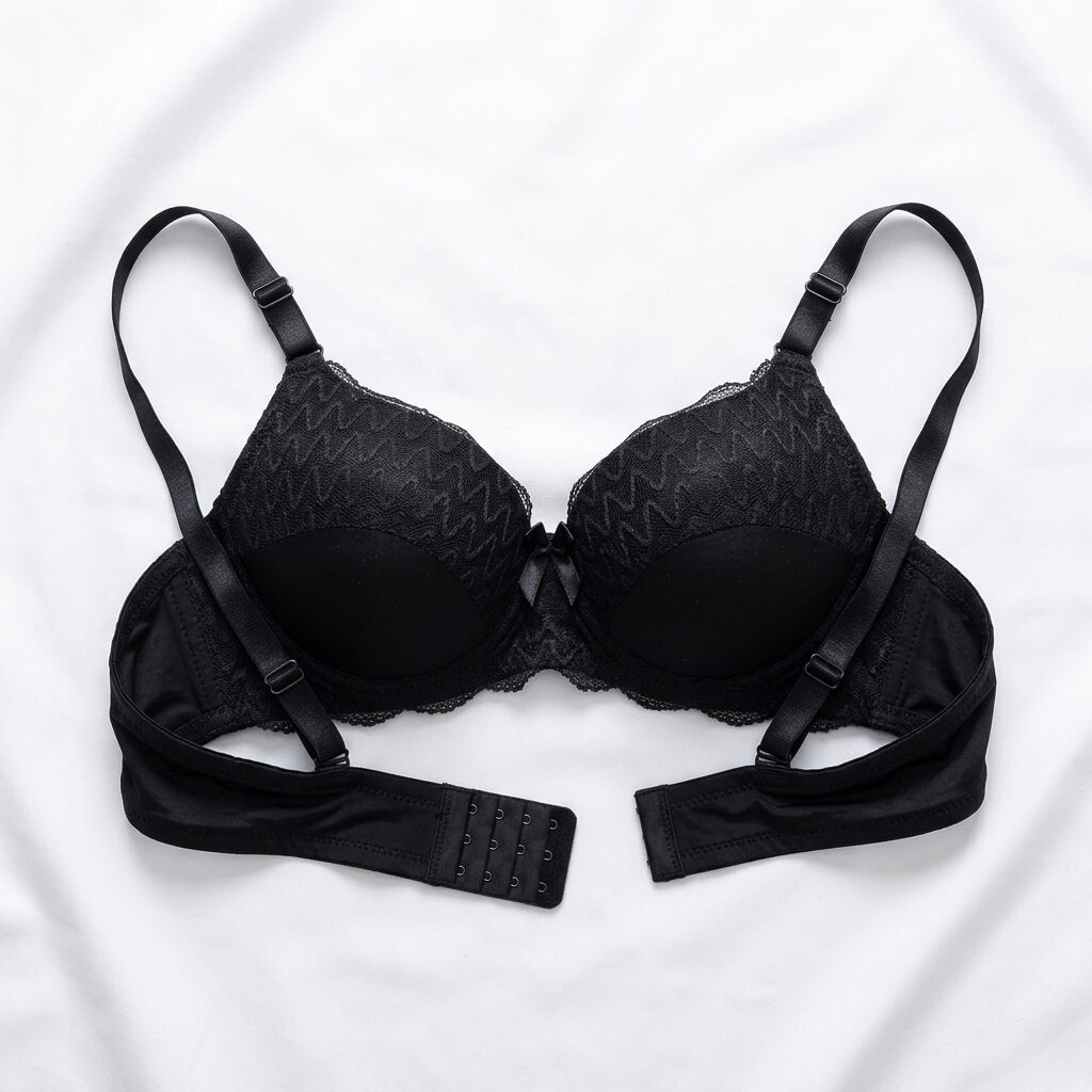 Black wireless bra with adjustable straps and a matching underband, laid flat on a white fabric background.