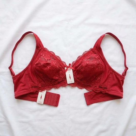 A red lace underwire bra laid flat on a white fabric background, with two paper tags attached and a matching red fabric insert piece beside it.